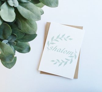 Kaart met envelop met Shalom (vrede) in gebroken wit met mintgroene letters en olijftakjes van Ahavah design