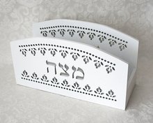 Matze standaard van wit hout met decoratieve uitsnijdingen van granaatappeltjes en het Hebreeuwse woord Matzah